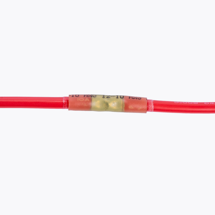 Close-up of a red electrical wire joined with a Cable Joiner Butt Splice 6mm yellow (5 Pack) connector, ideal for secure connections in camping power and LED lighting solutions by Innovative 4x4.