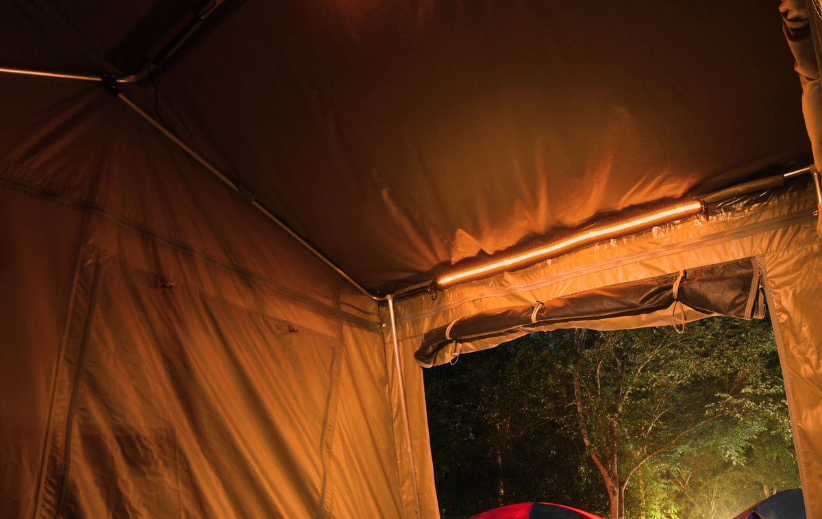 Interior view of a tent illuminated by a warm LED light strip mounted along the roof edge, showcasing camping lighting solutions for outdoor adventures.